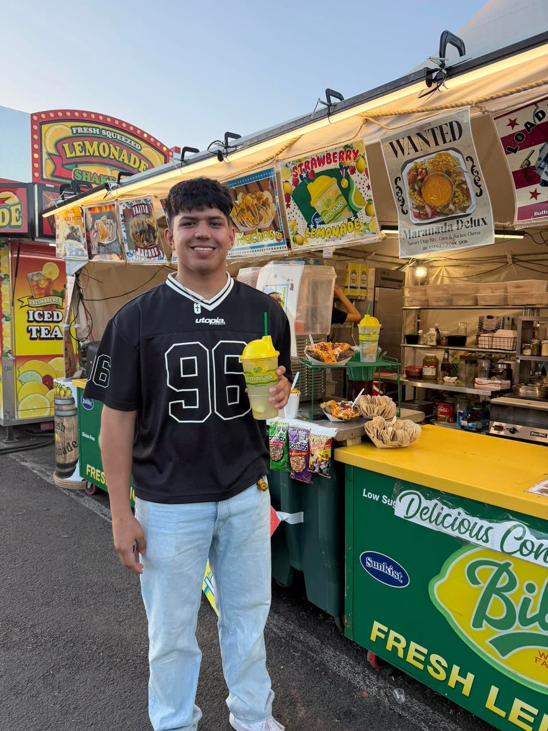A customer holding a frozen Bill's lemonade in front of the stand